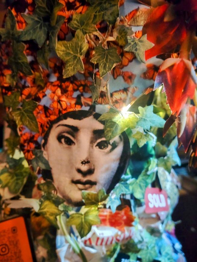 Close detail of a collage sleeve with a face, leaves, flowers and vivid paper fragments.