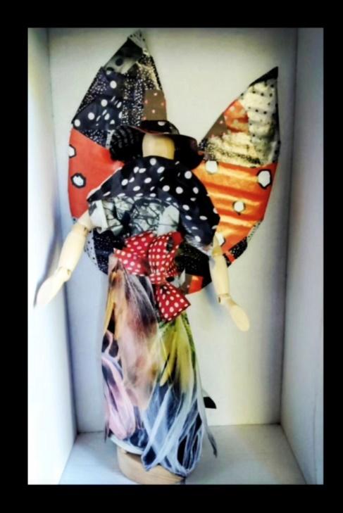 A small fashion fairy assembled from patterned collage materials.