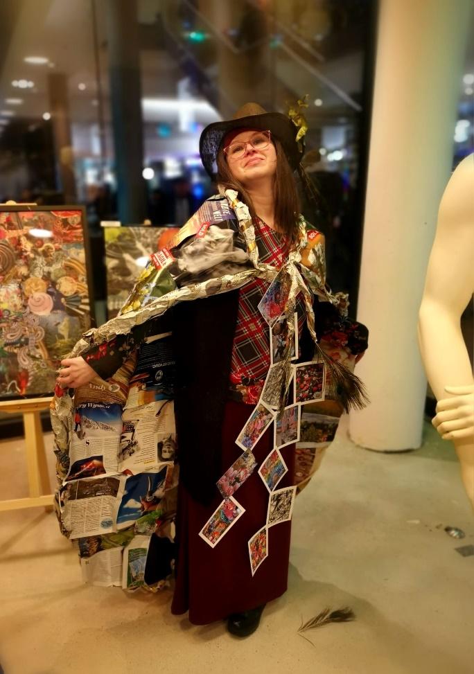 Rita Rozynek wearing a collage fashion costume in an exhibition space.