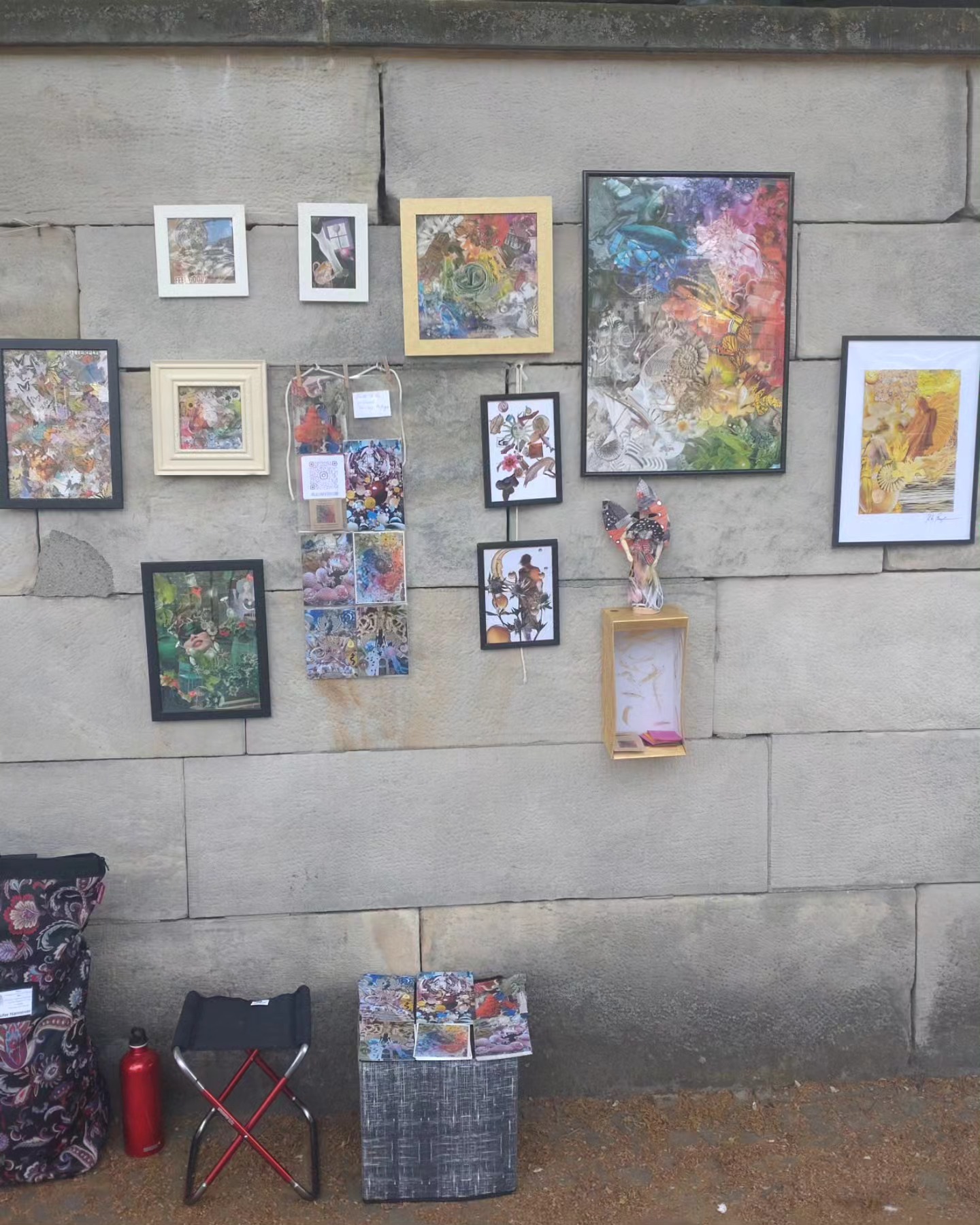 Framed artworks displayed on the stone wall at the open-air Kunstufer Hannover exhibition.