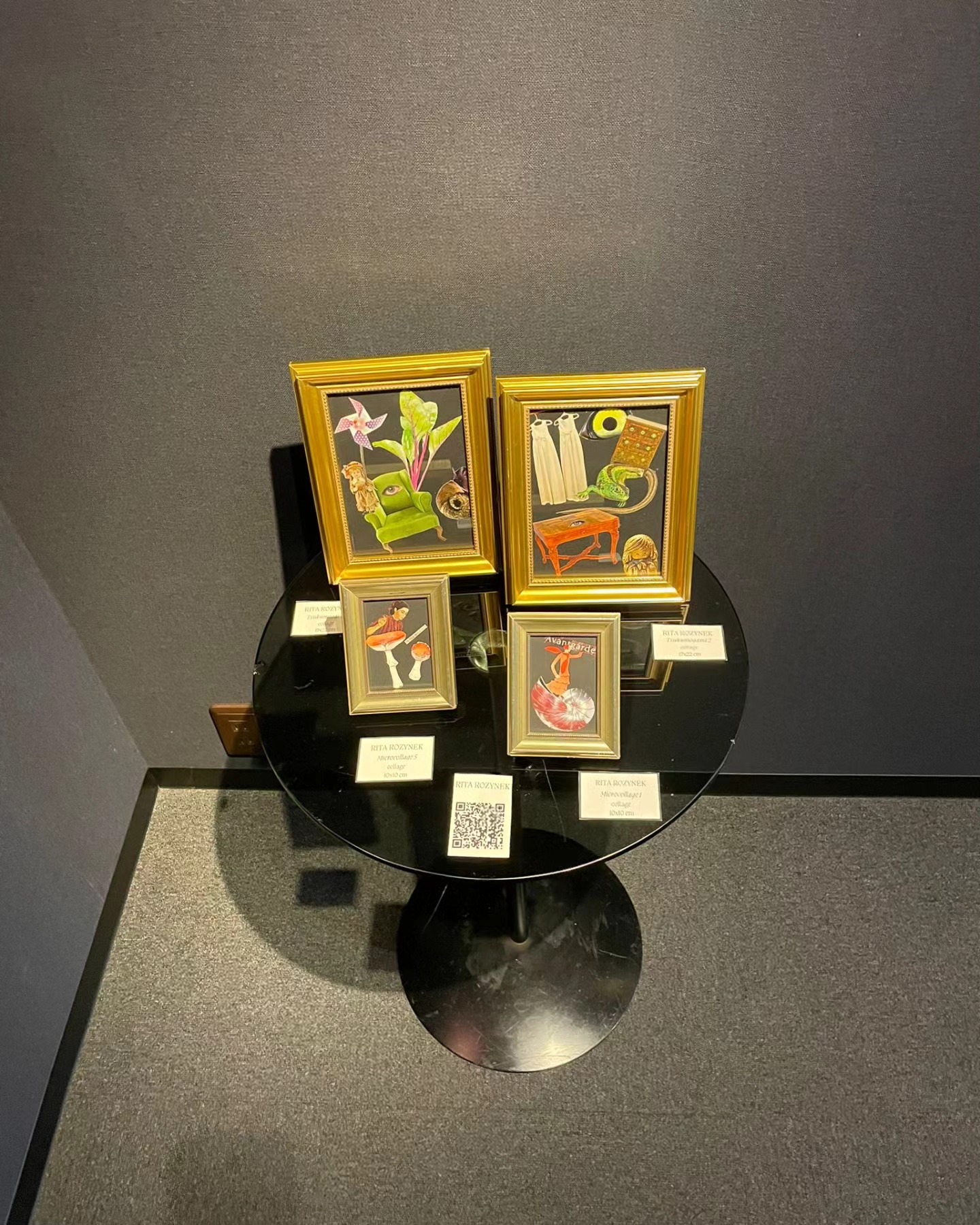A high-angle photograph of four framed collages displayed on a round black glass table at the SOUL – Tsukumogami exhibition in Osaka, Japan.