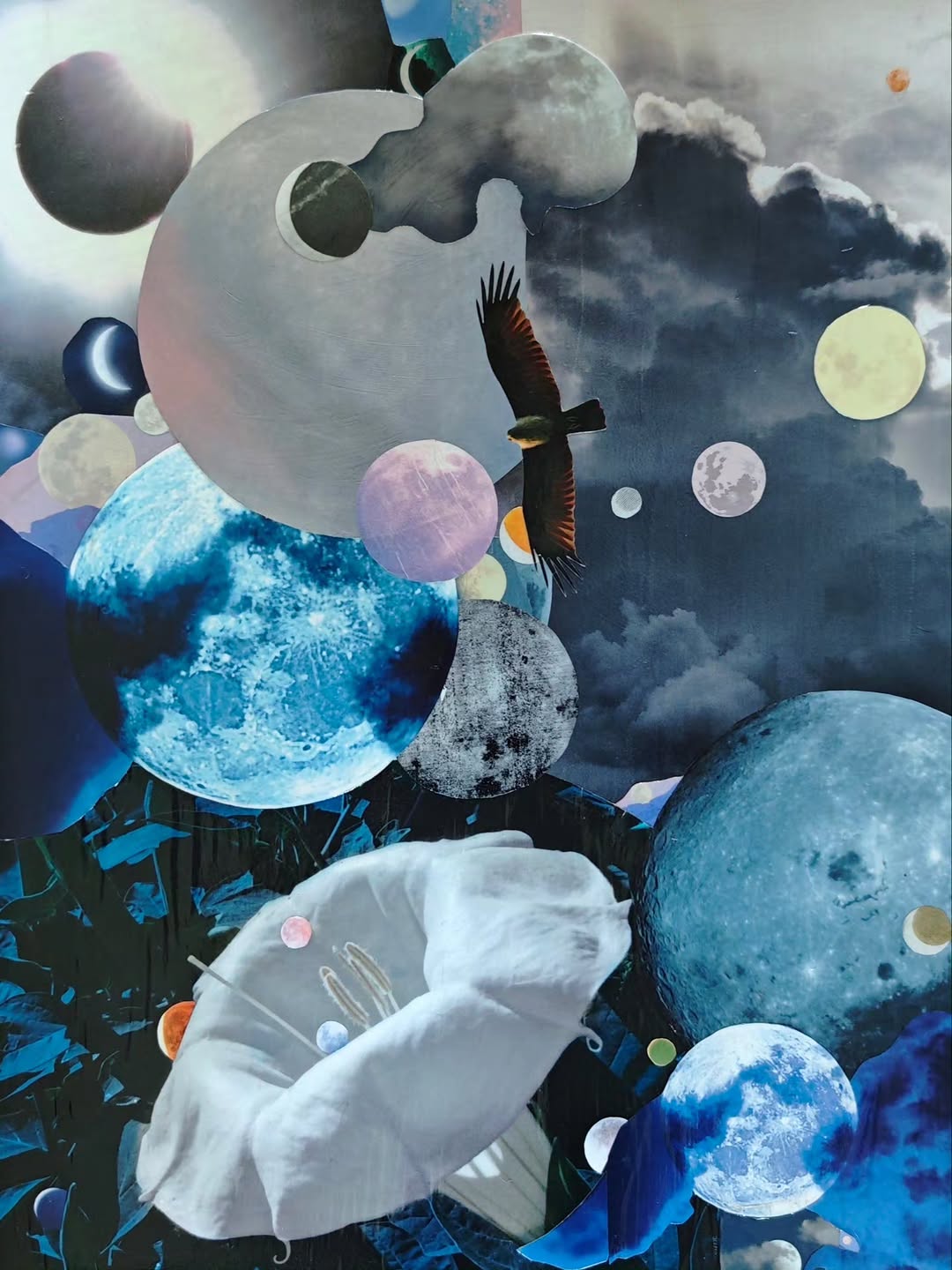 Moon Light - Moon Darkness, an analog collage of moons, clouds, planets, and a bird in a blue night sky.